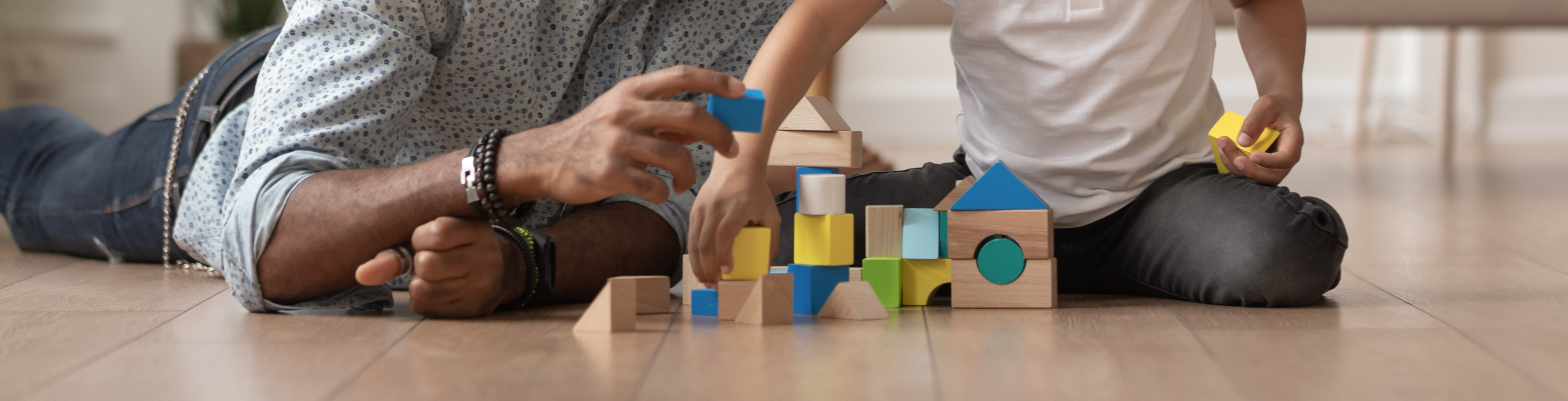 A father playing and arranging blocks with a child.