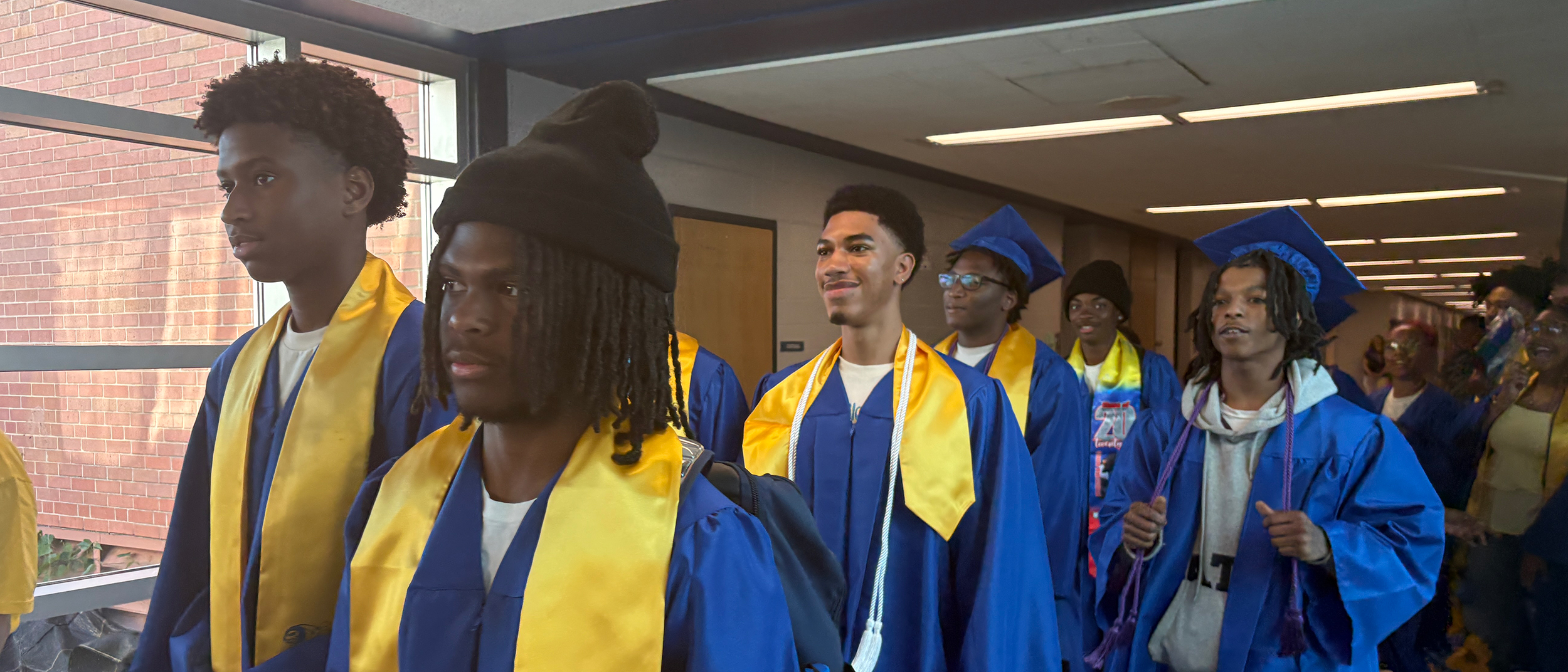 CHS students walk down the hallway in their graduation caps and gowns.