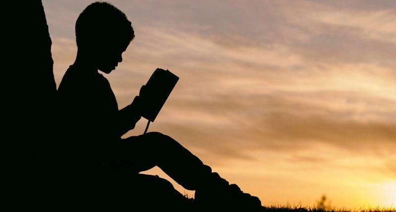 boy reading book in sunset