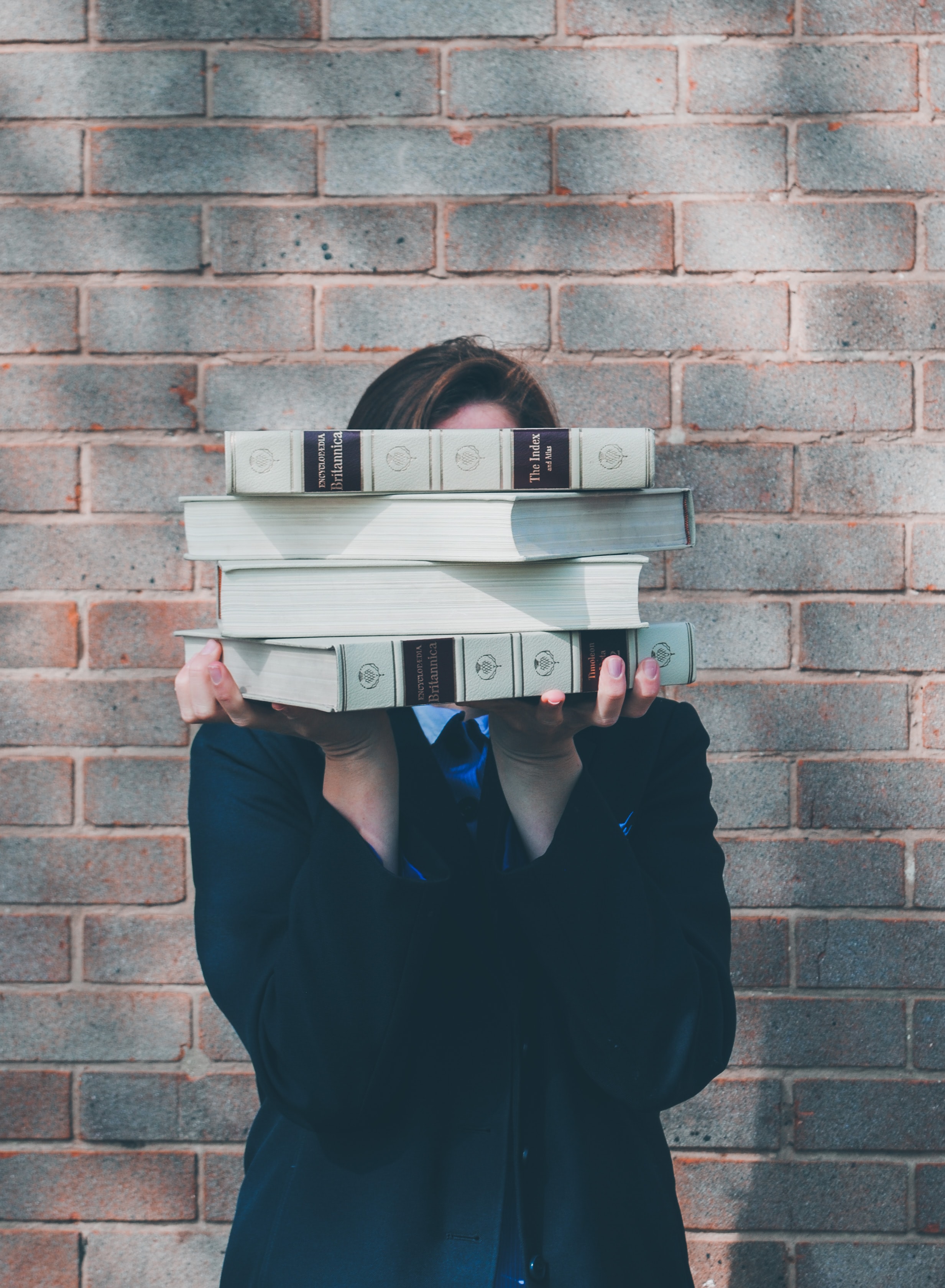 student with books covering face