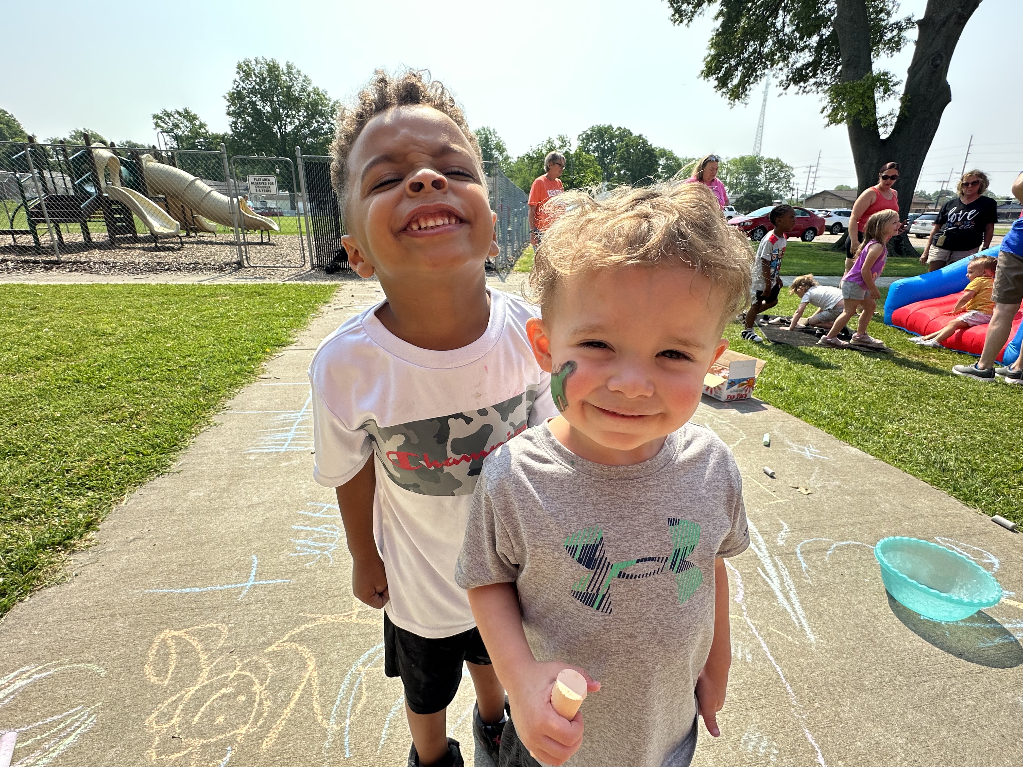 Two young children are smiling for the camera on the playground