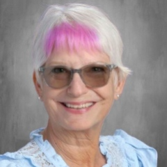 A smiling teacher with gray and green hair