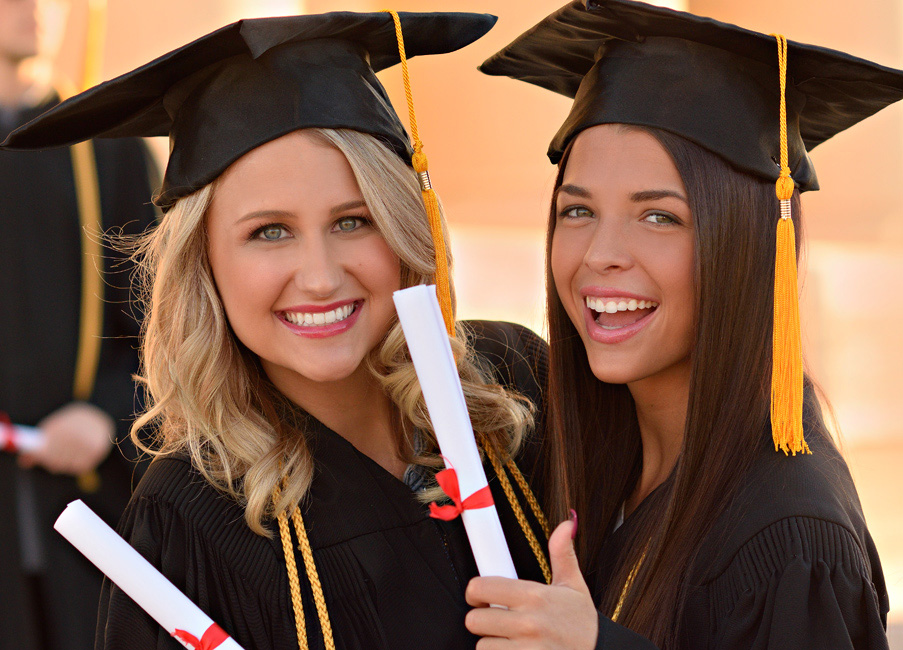 picture of two female students in cap and gowns with diploma