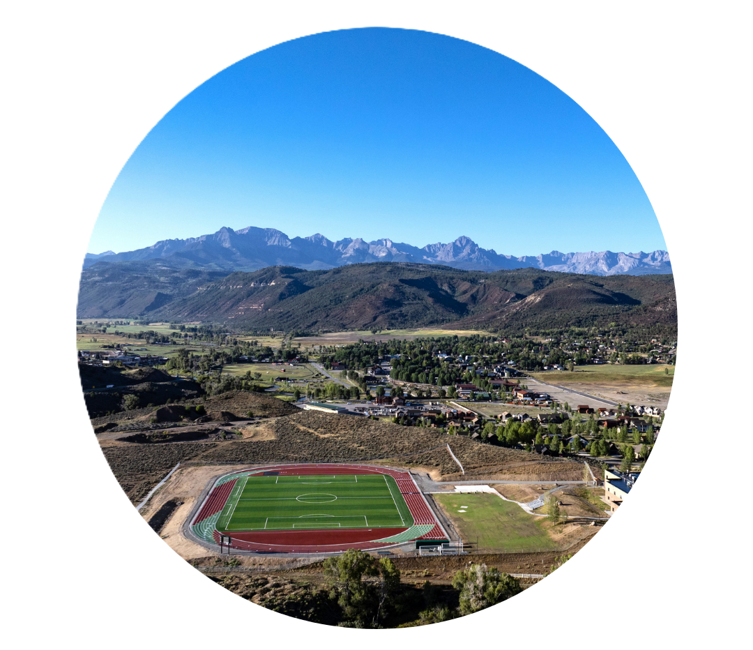 Circular view of the Cimarron Athletic field with track, town, and mountains in the background.