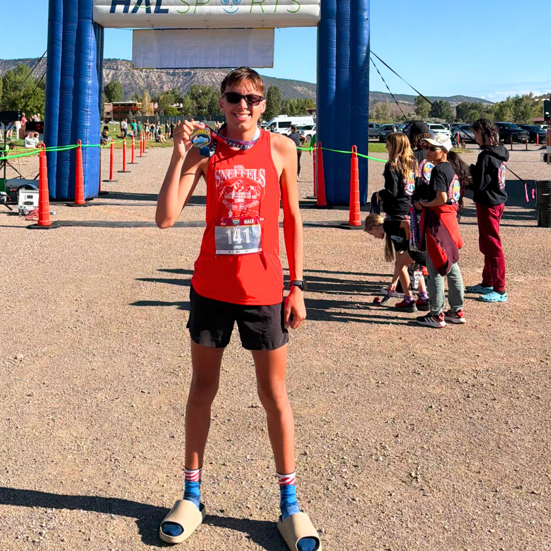 Runner holding a medal at the Mt. Sneffels Half Marathon finish line.