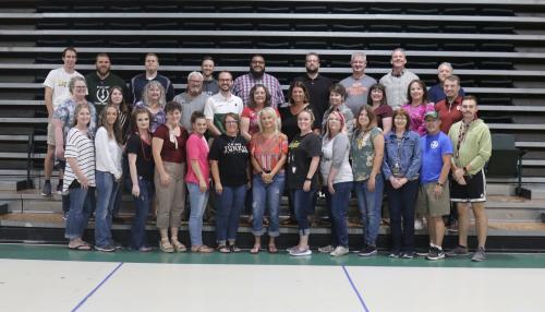 wells middle school staff standing in front of school gym benches