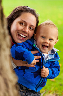 Photo of a mother holding a baby in a blue jacket.