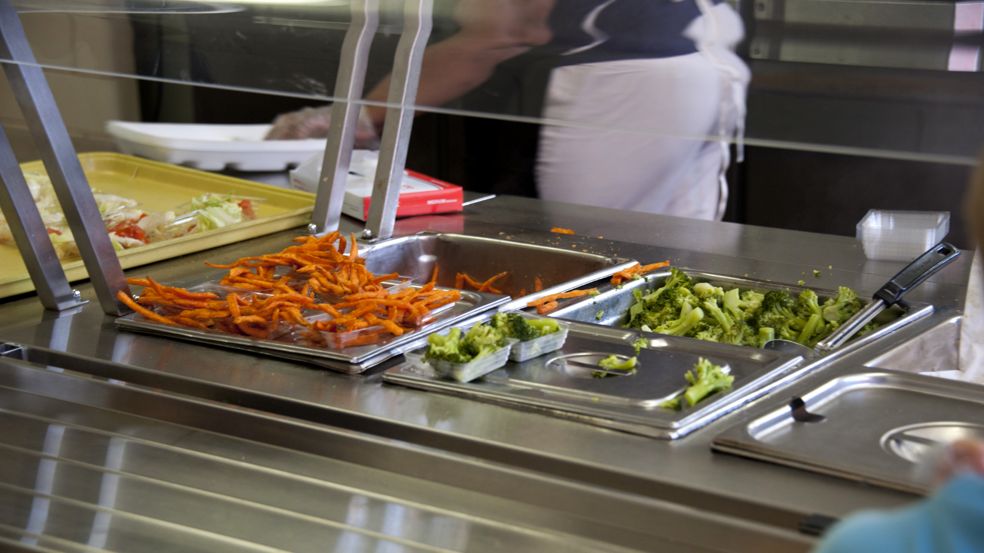 Photo of the lunch room serving counter with broccoli and sweet potato fries.
