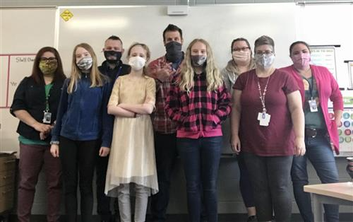Photo of staff and students wearing masks in front of a white board.