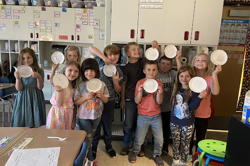 10 students holding empty paper plates in a classroom.  This is to show the clean plate club members.