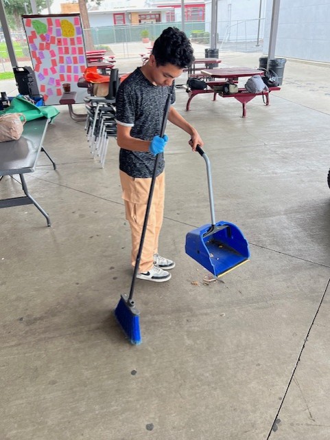 Mark Twain student sweeping up trash on campus