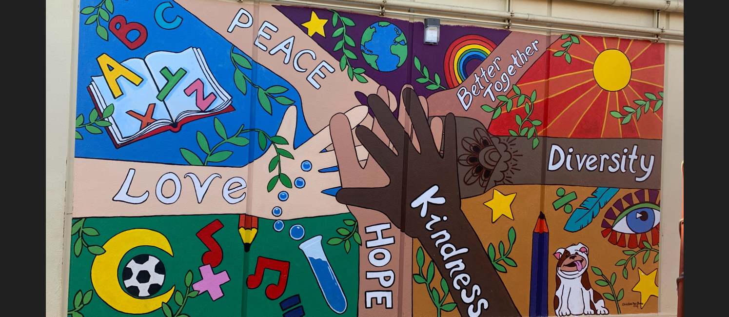 Colorful mural showing hands of different skin colors with the words "peace, hope, diversity, kindness, love, hope". Surrounded by colorful  images of math, science, sunshine and a bulldog mascott. 