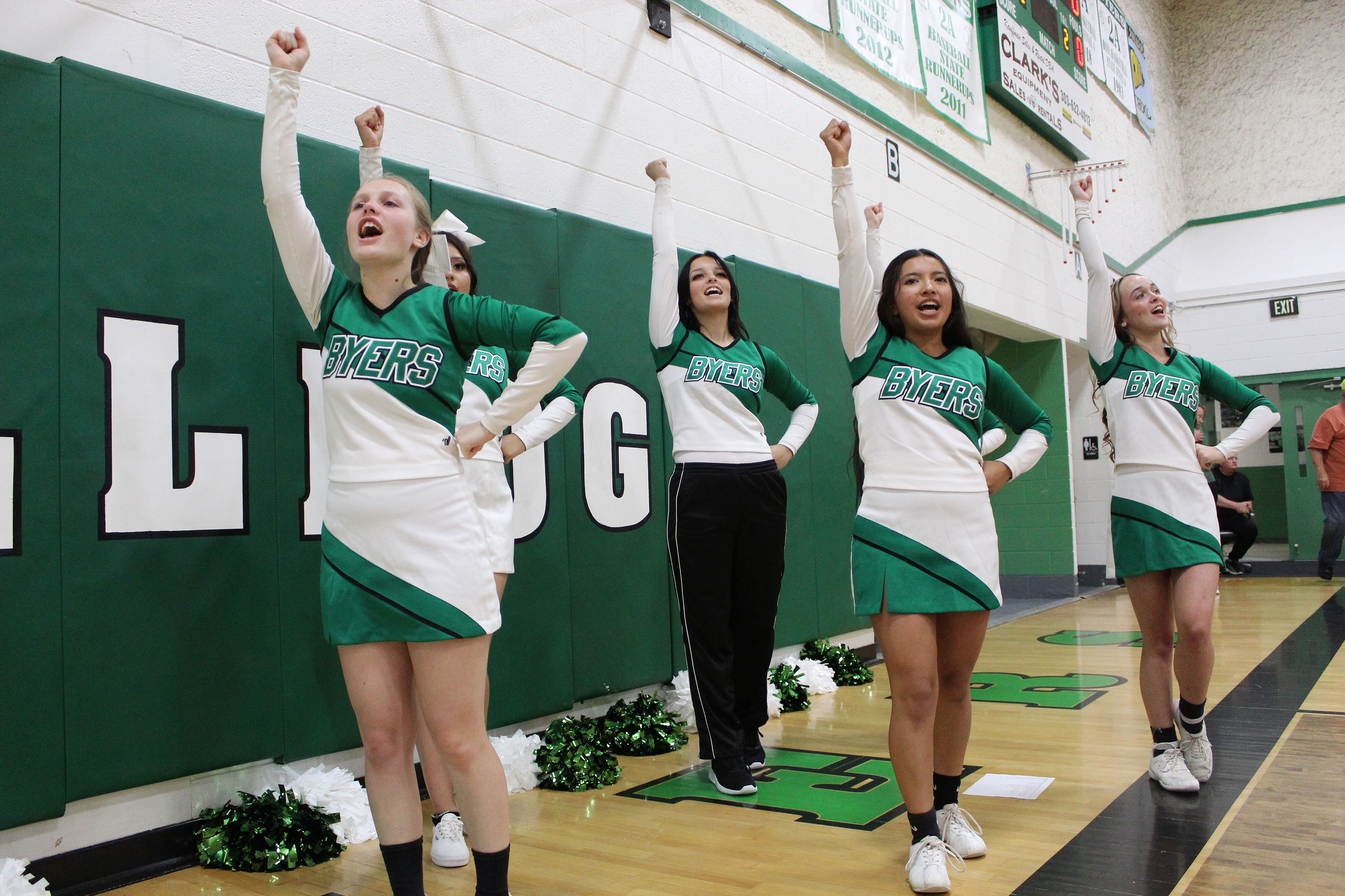 Cheering on our team at the volleyball game. All the girls with one arm up and white uniforms.