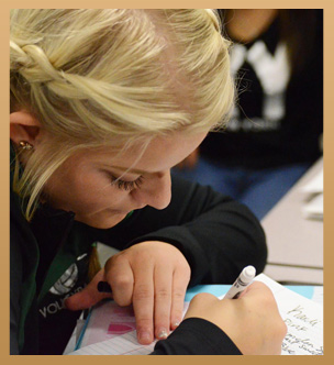 a girl writing on notebook paper in black marker