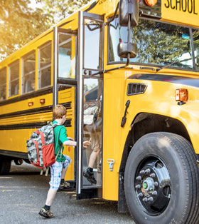 a small boy stepping onto a yellow schoolbus