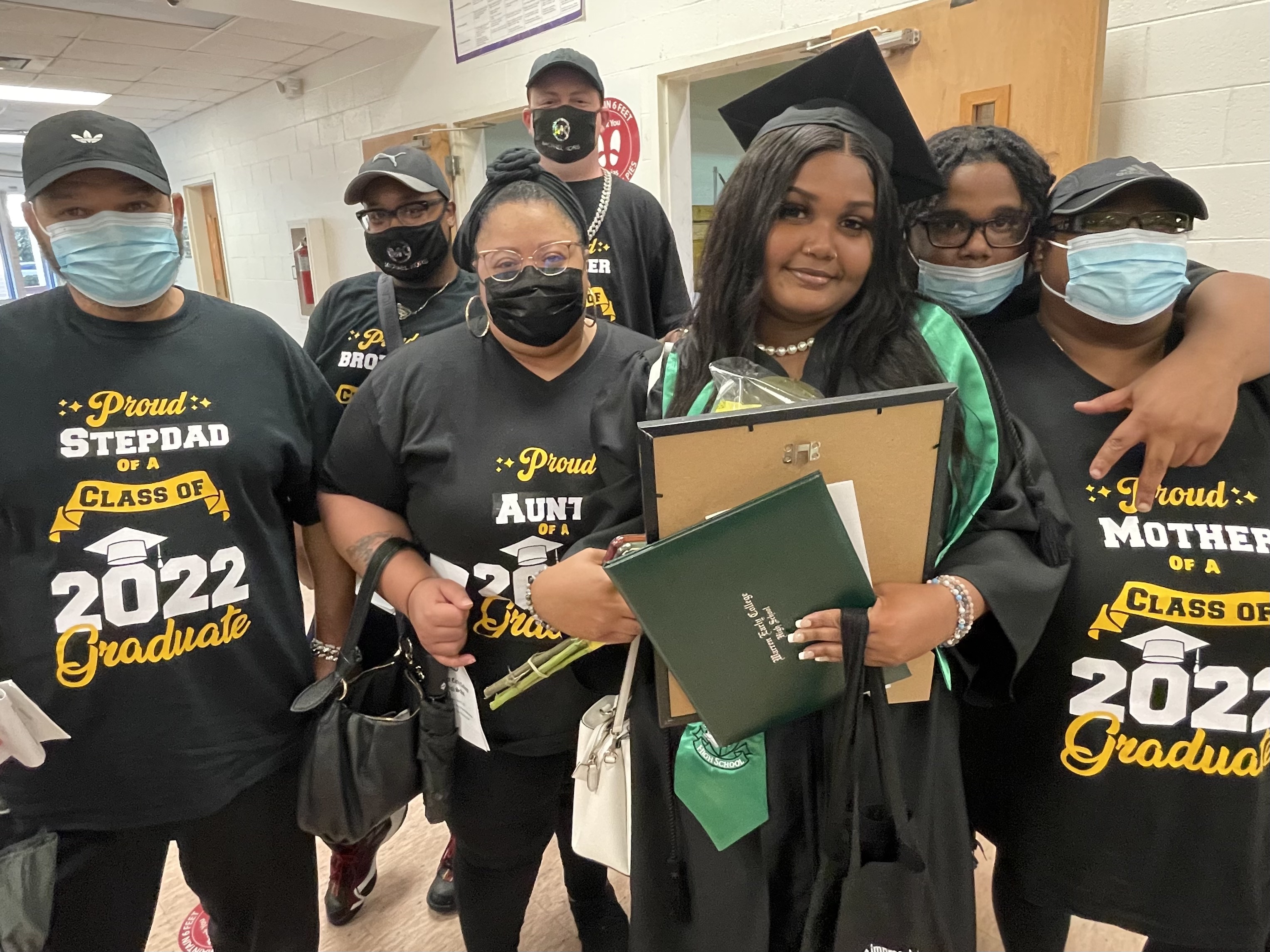 graduate surrounded by family wearing personalized shirts identifying themselves as family members of a graduate in the class of 2022