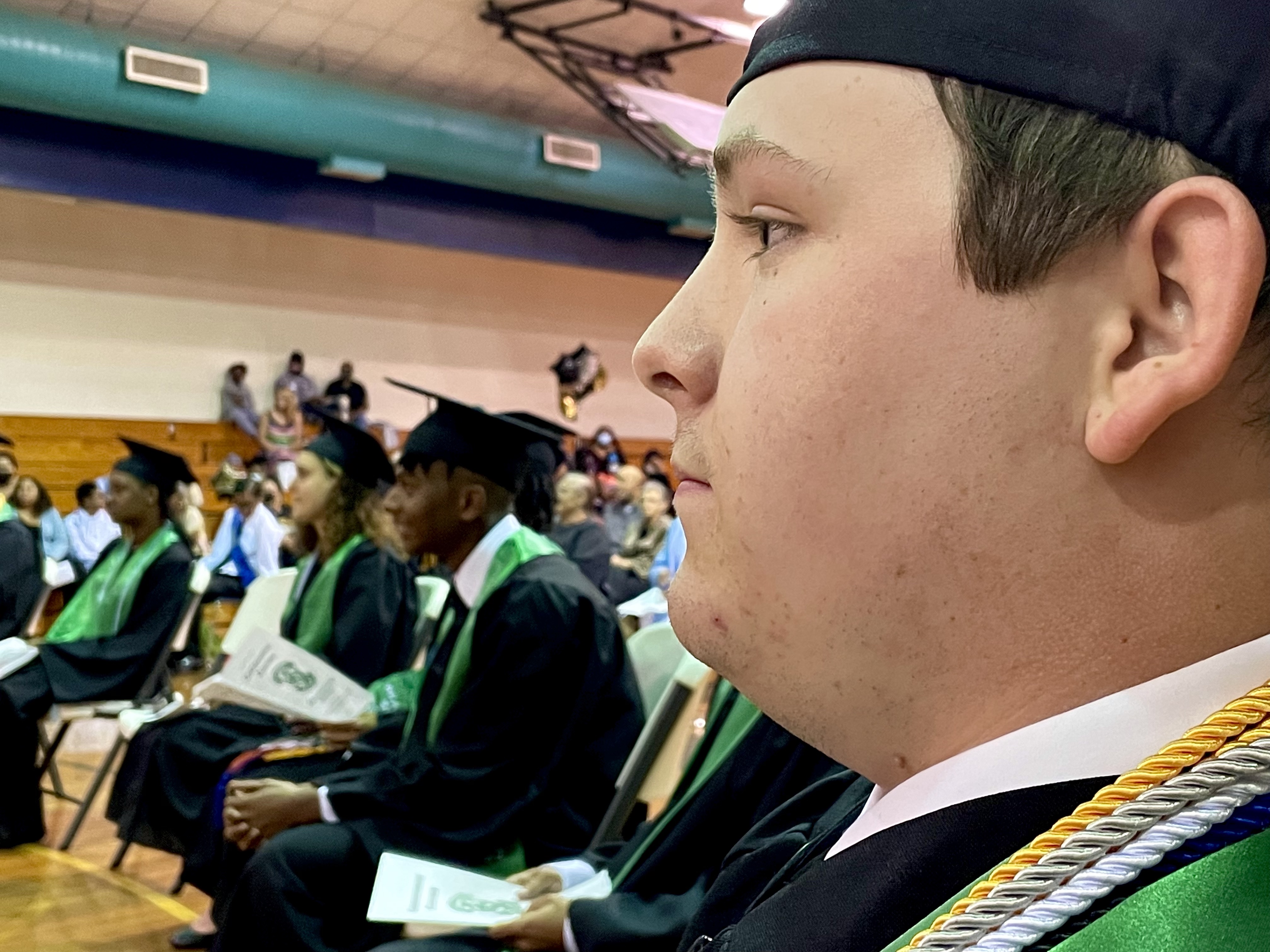 graduate wearing a cap with other graduates in the background