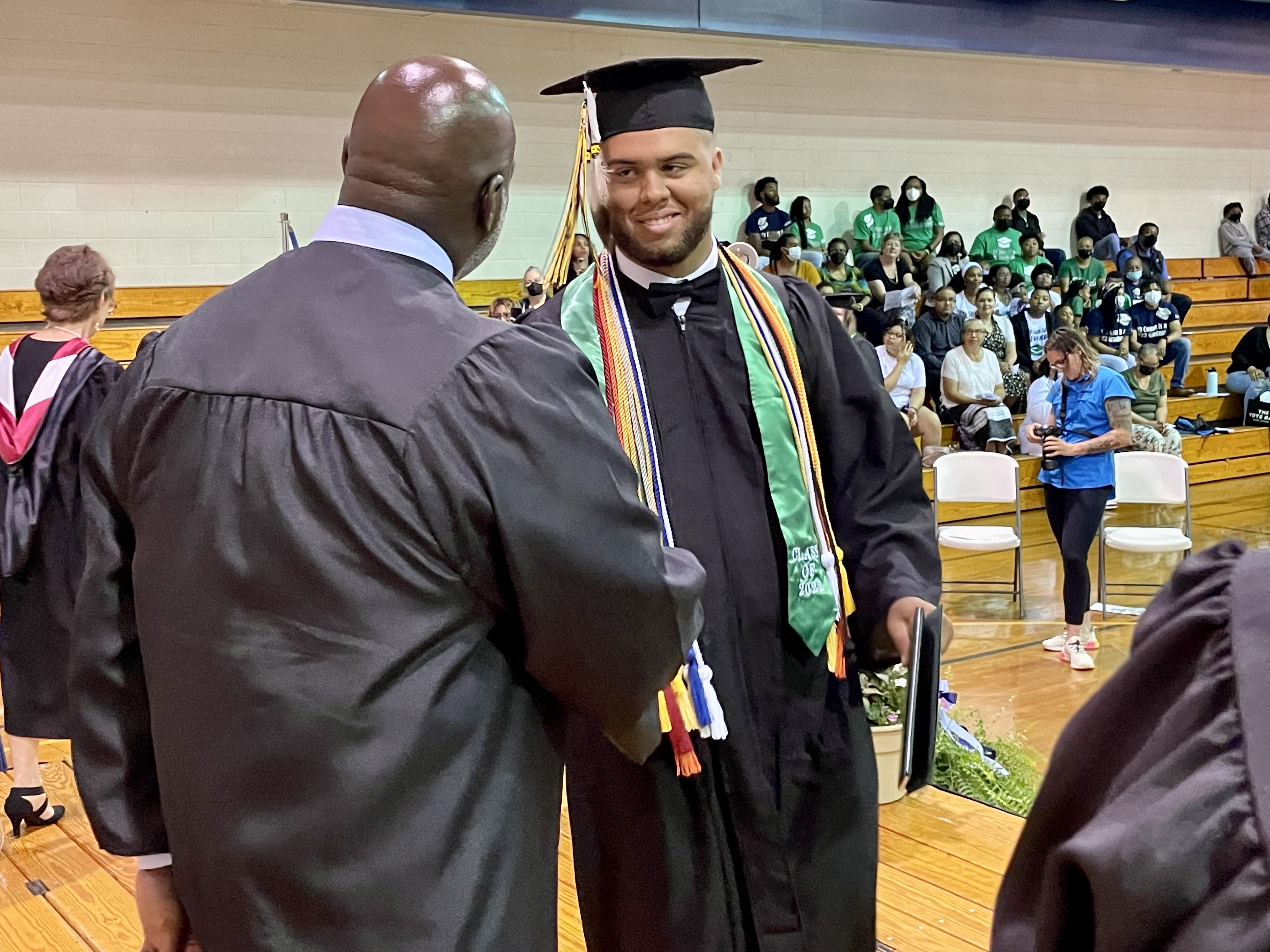Superintendent Sutton shaking hands with a graduate receiving a diploma