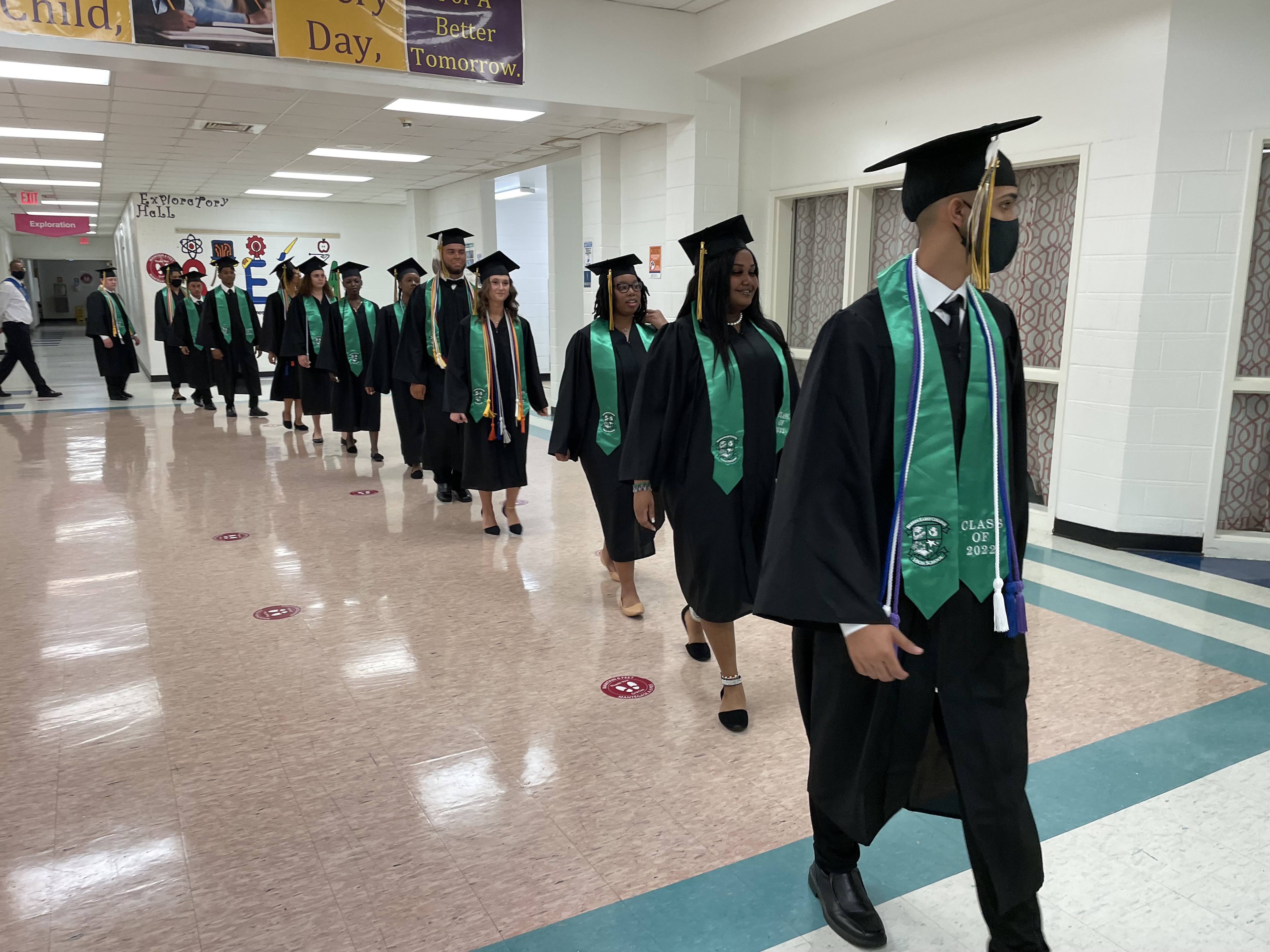 line of students wearing caps and gowns walking into graduation