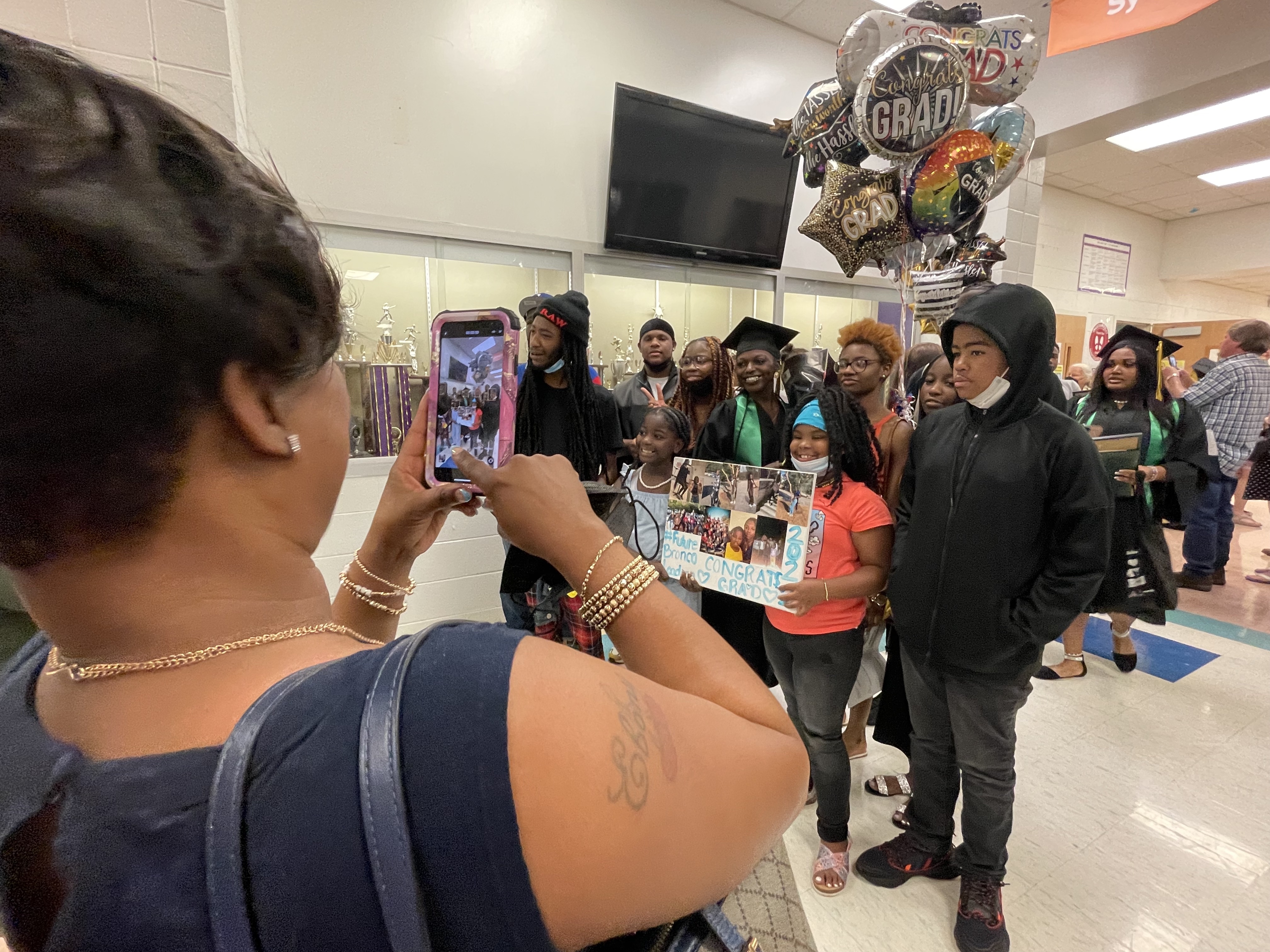 woman taking a picture of a graduate surrounded by family and friends