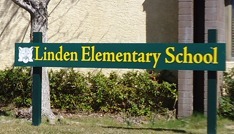 a green sign that reads "Linden Elementary School" in yellow letters