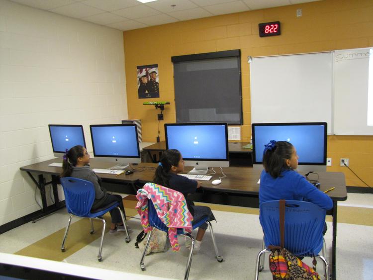 kids and teacher in front of computers learning