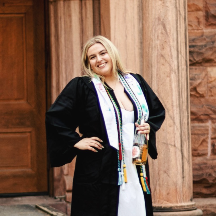 white woman posing in a lbacn and white graduation gown