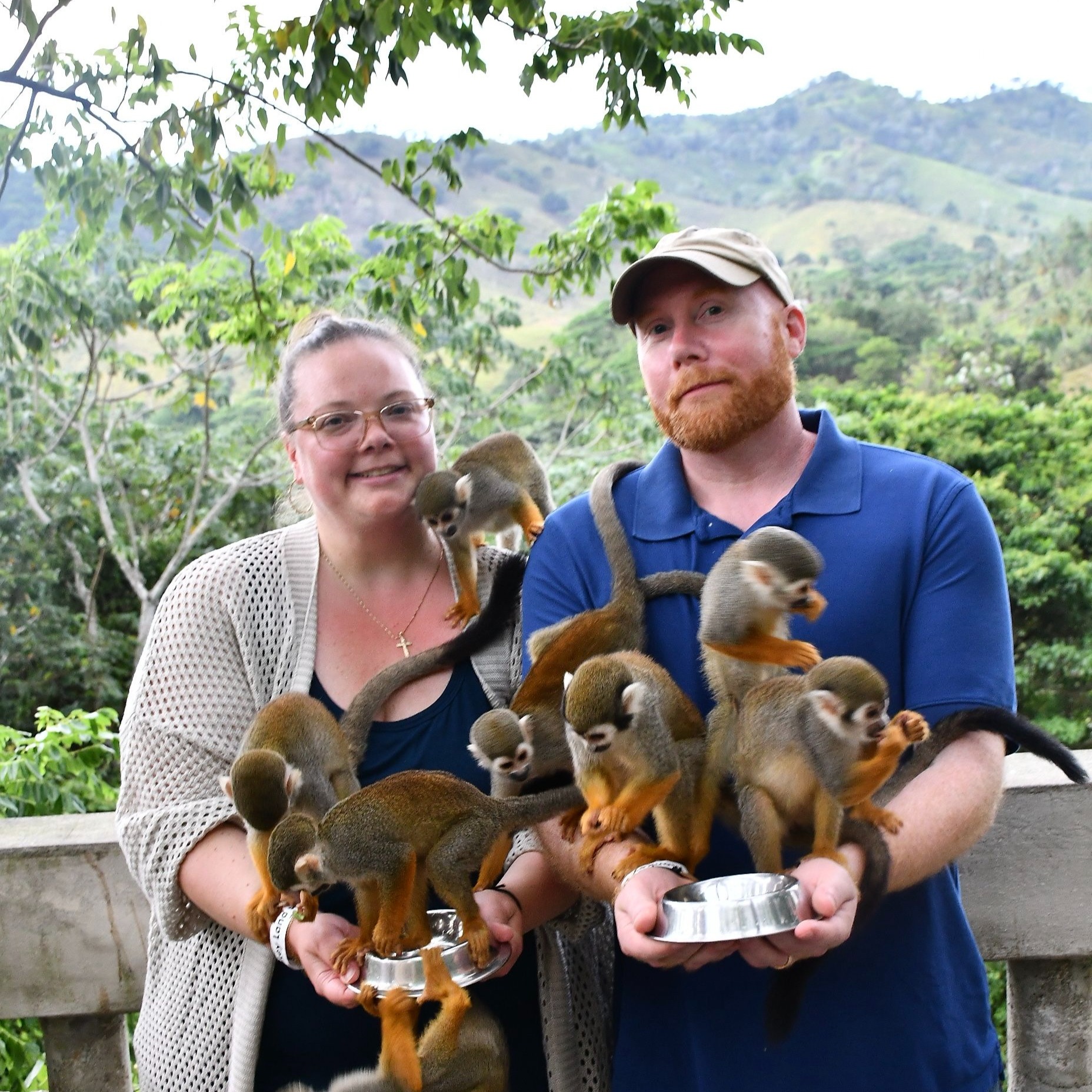2 people smiling at the camera holding monkey
