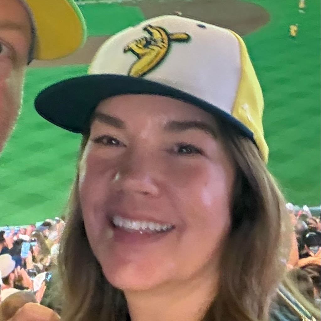women in baseball cap smiling at camera