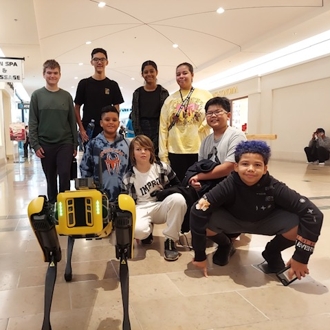 group of teen posing with a robot