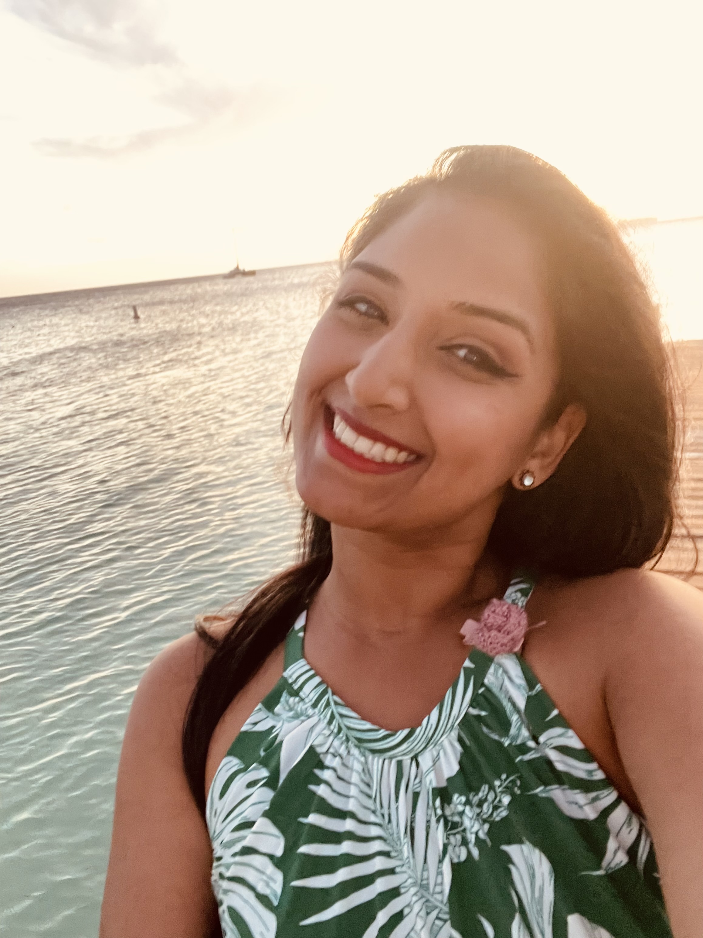 femalte standing in front of a body of water smiling