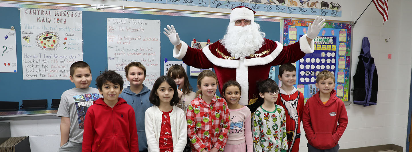 A group of 3rd graders posing with Santa.