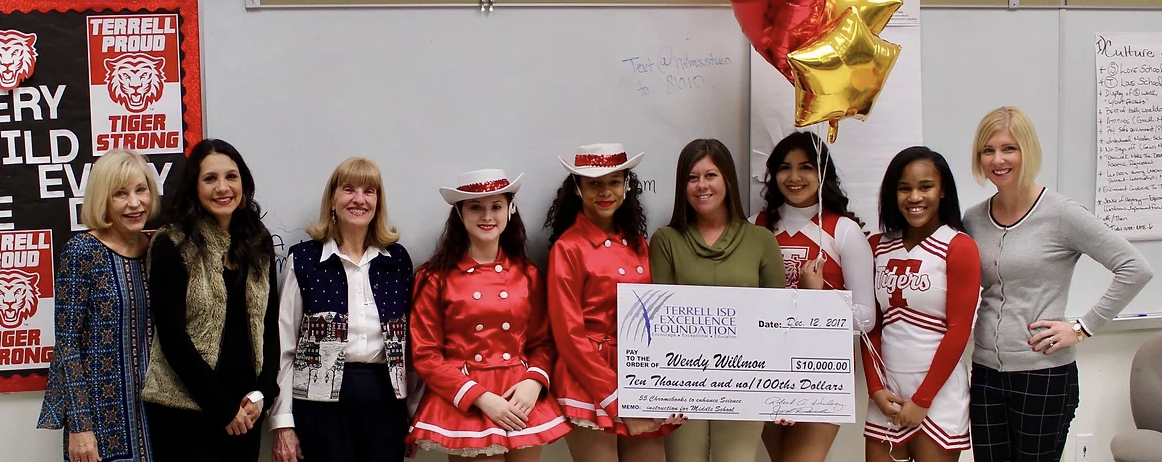 science teacher, staff and students taking picture with big check