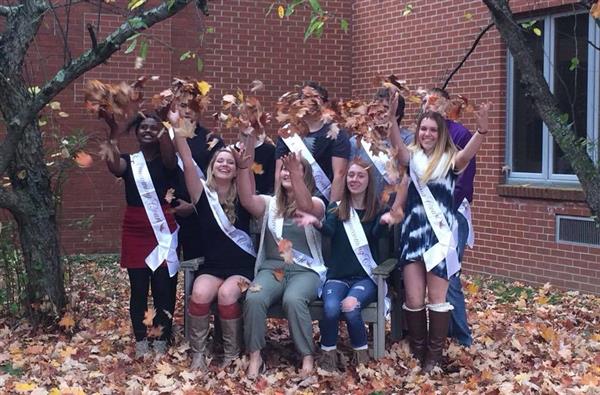 Group of students throwing leaves to the air