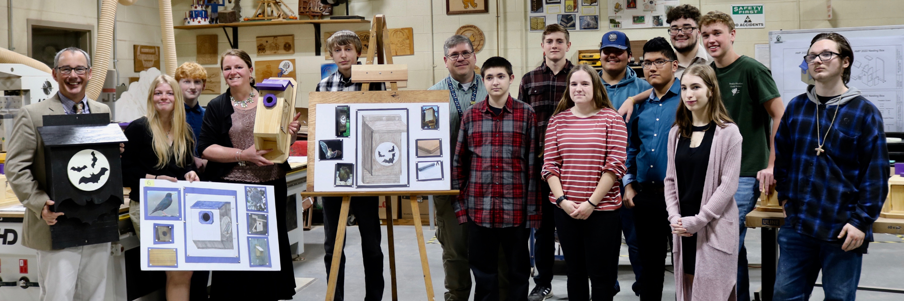 Students posing by display board