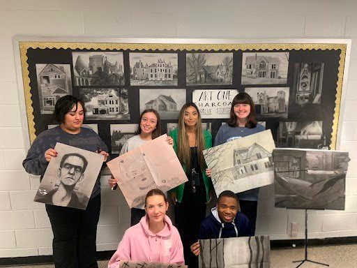 Teacher and Students posing with artwork in front of a bulletin board