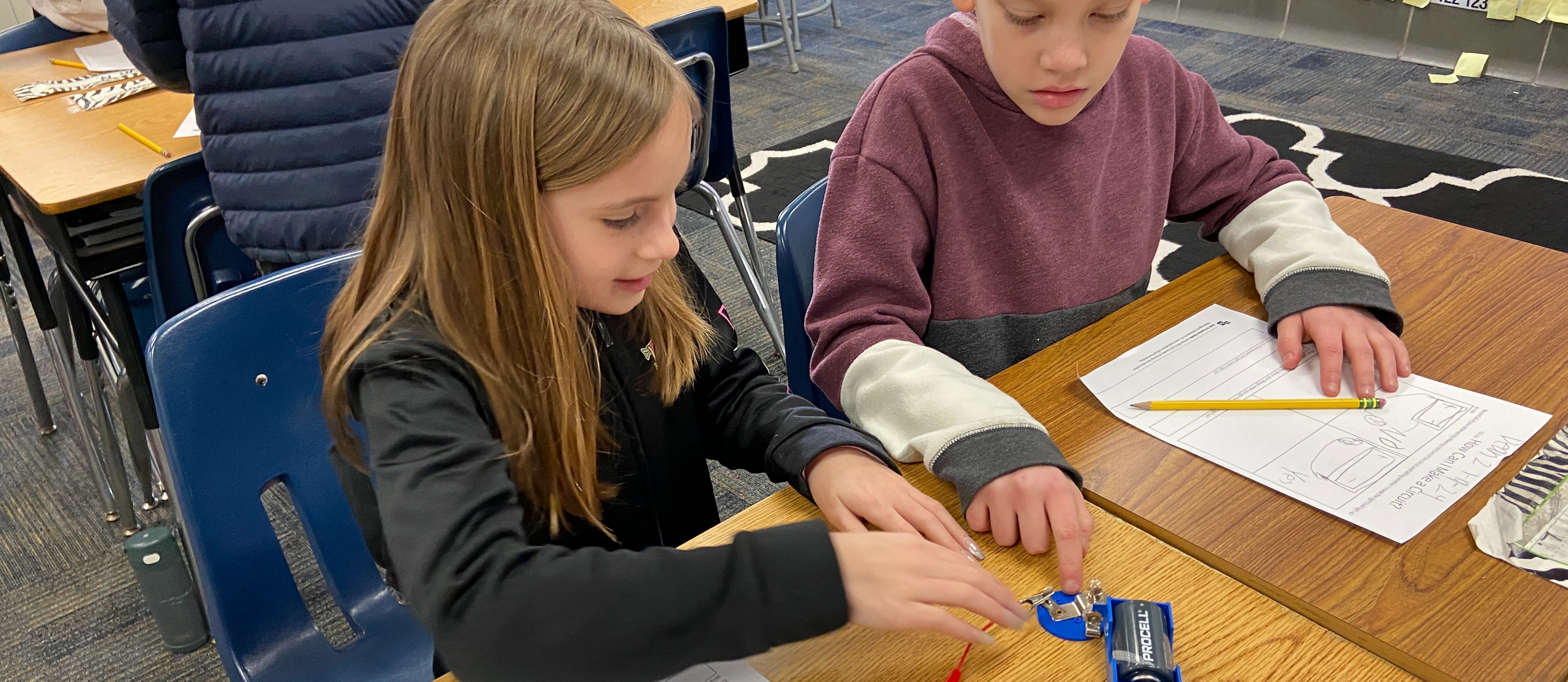 Students use a battery and wire to try and light a small light bulb.