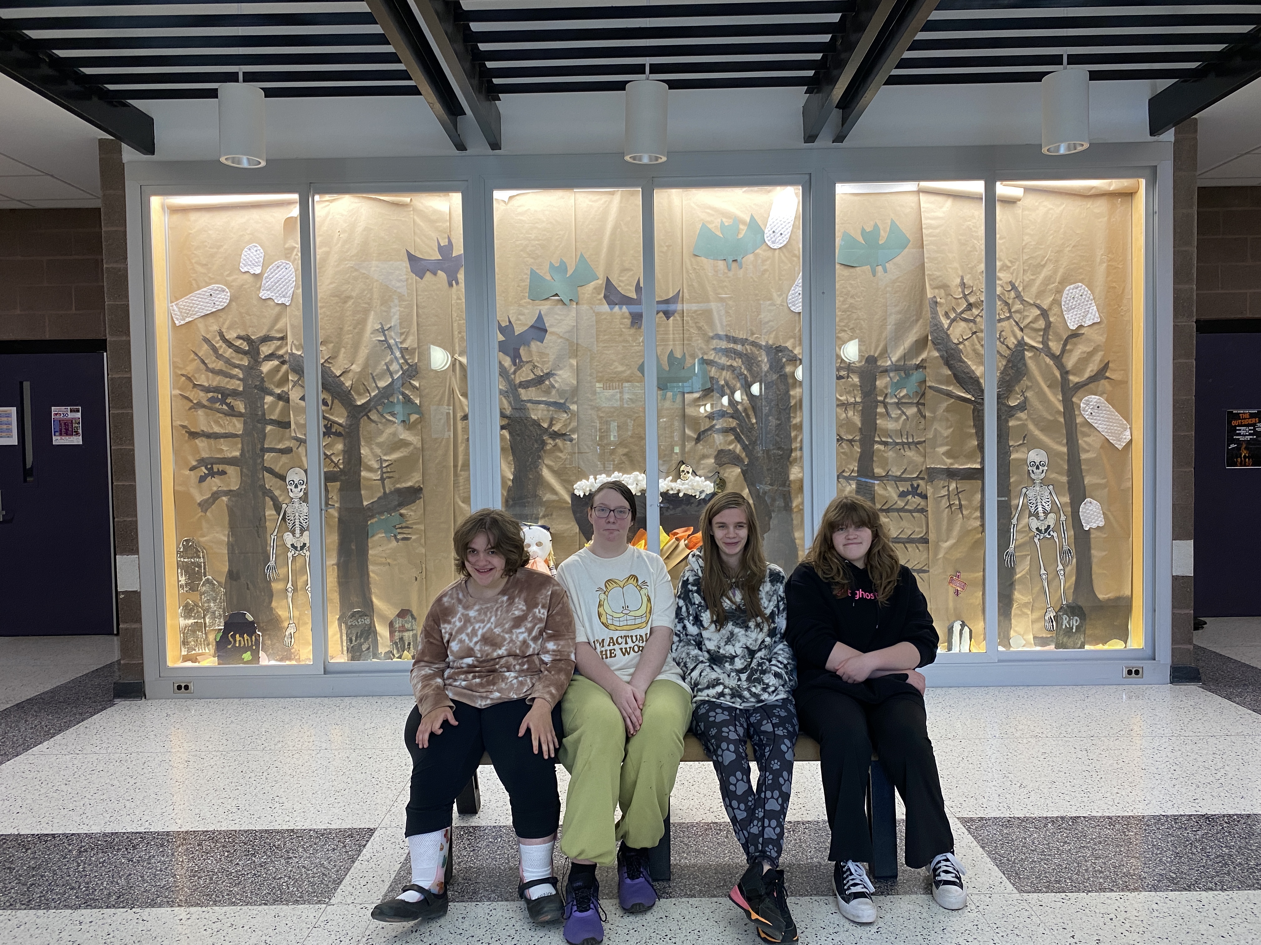 Four students sit in front of a halloween display