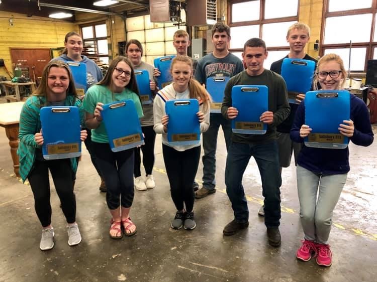 FFA members holding blue clipboards posing for a group picture