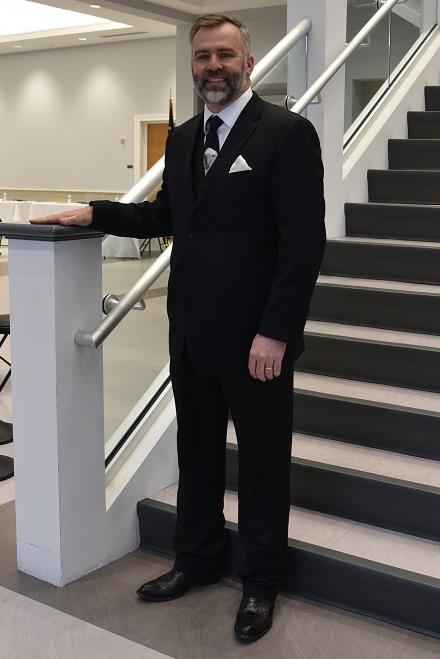 greg head standing on stairs wearing a suit