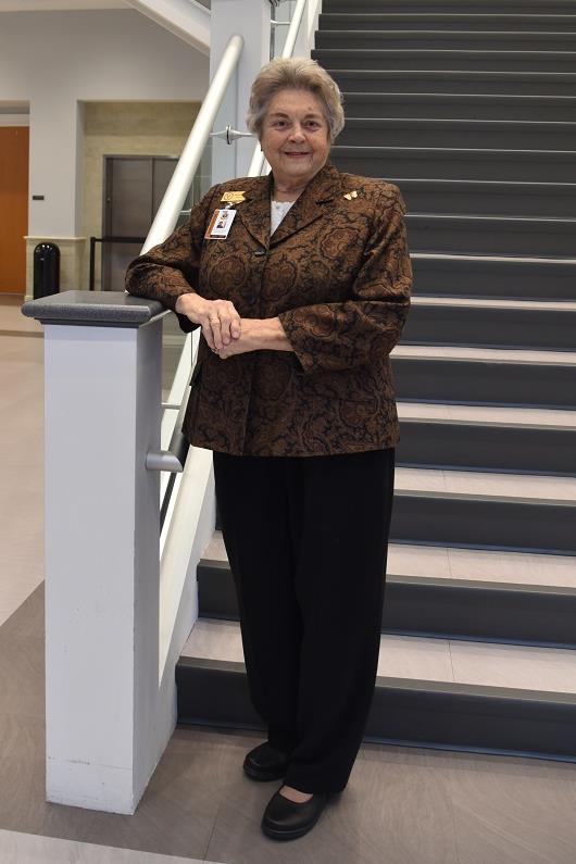 priscilla doster standing on stairs wearing a brown blazer