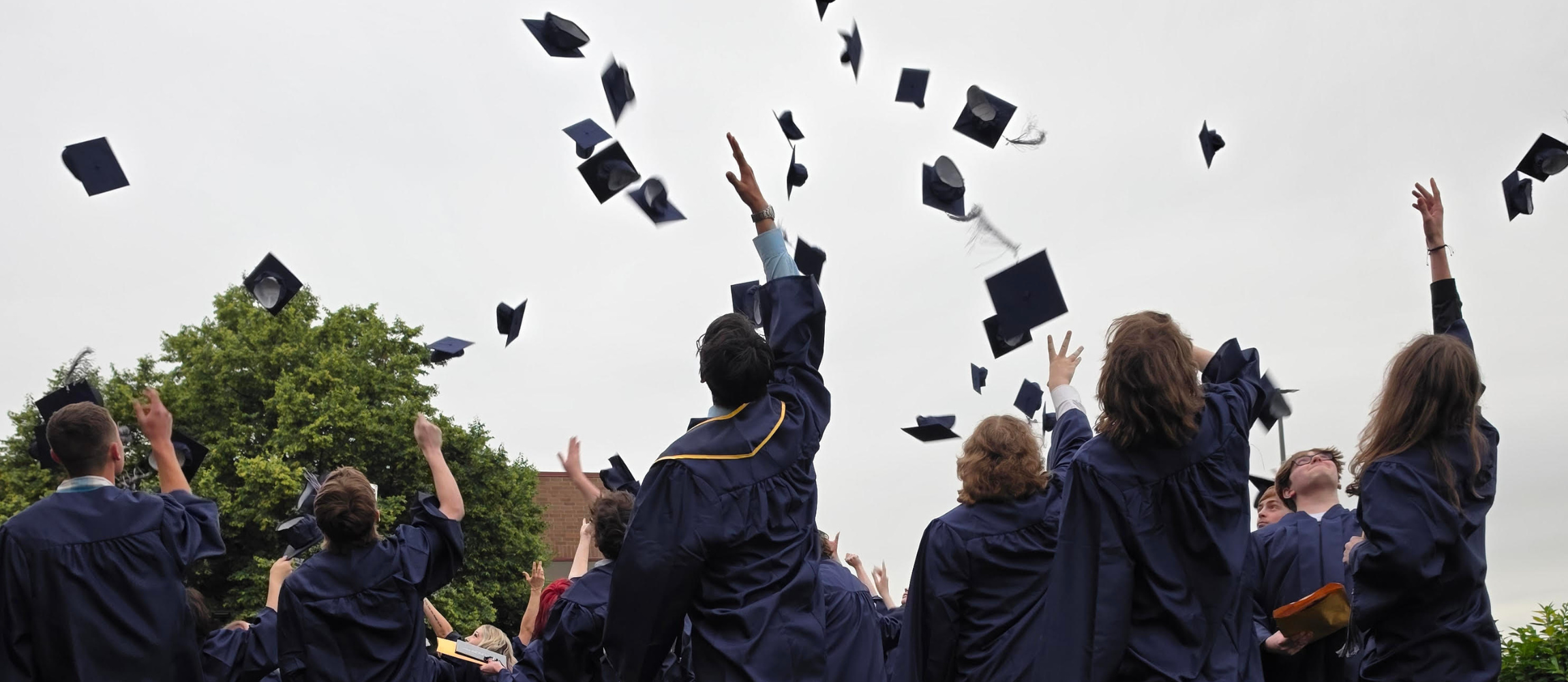 graduates launch their caps toward the sky