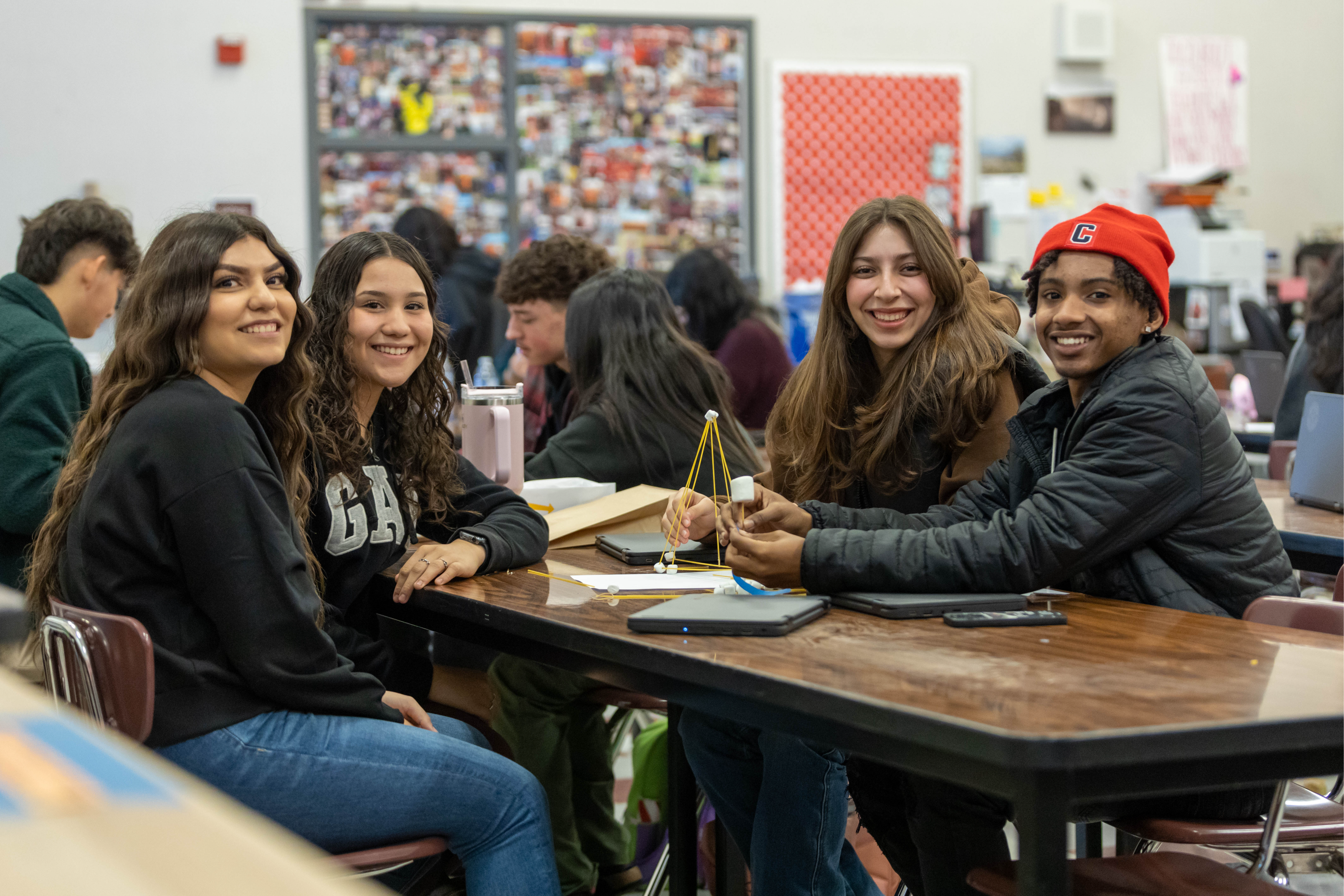 Four high school students work on group project at table