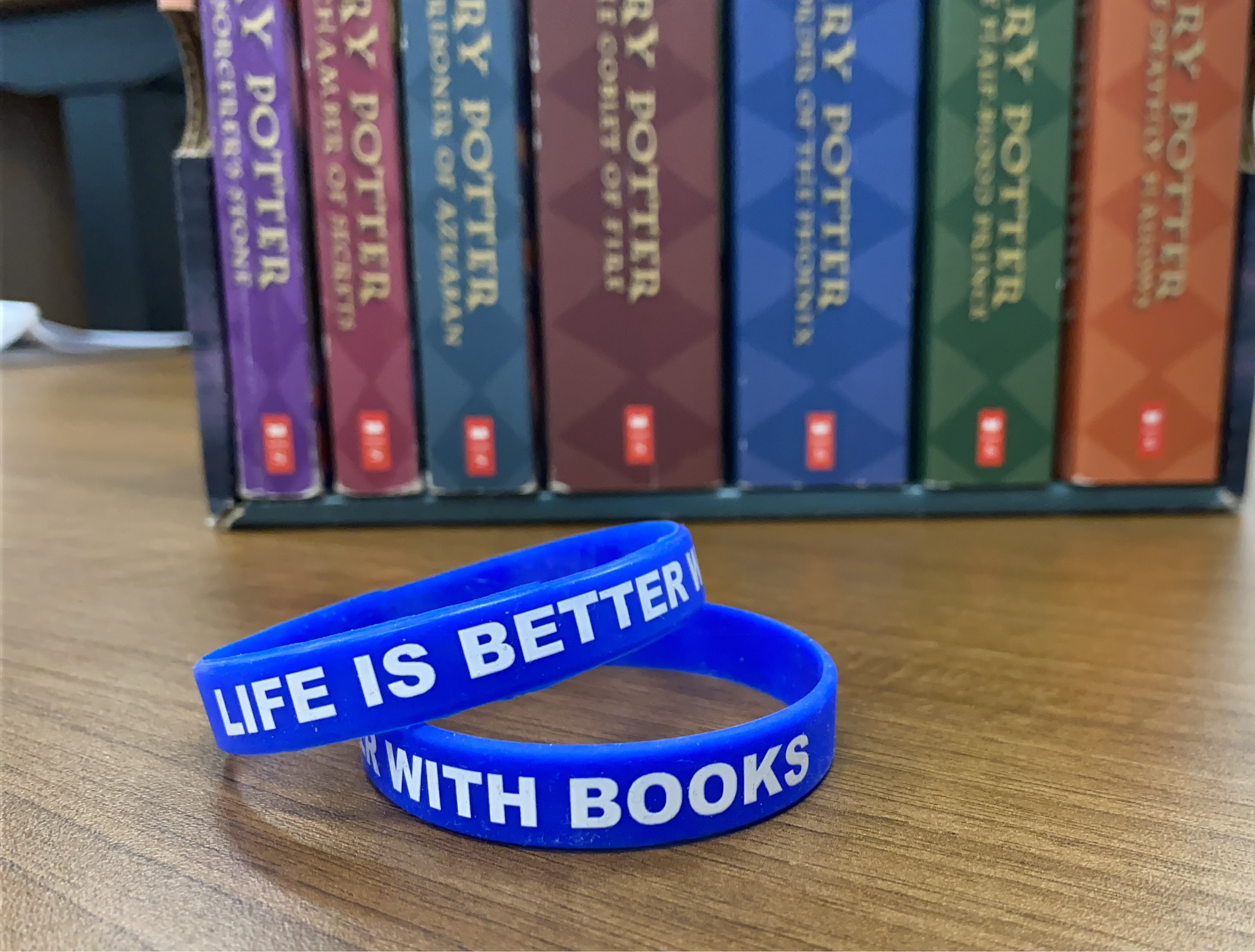 Blue silicon wristbands with white letters, "Life is better with books"