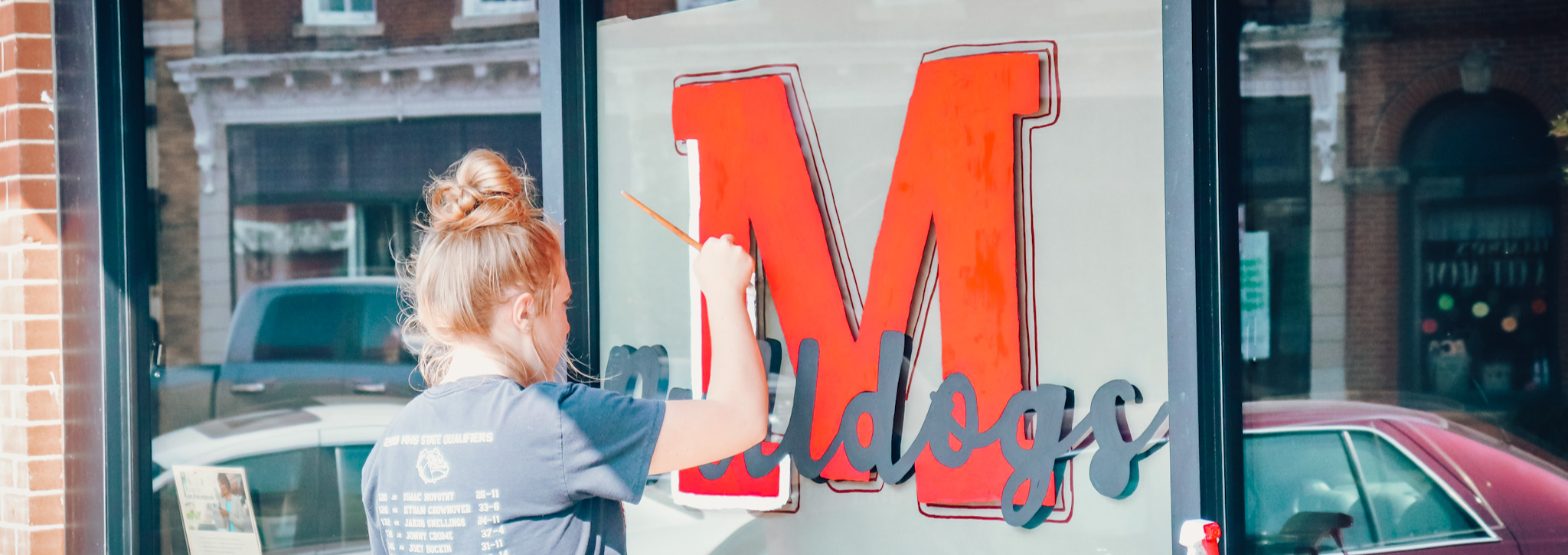 individual painting letter M logo on small business window
