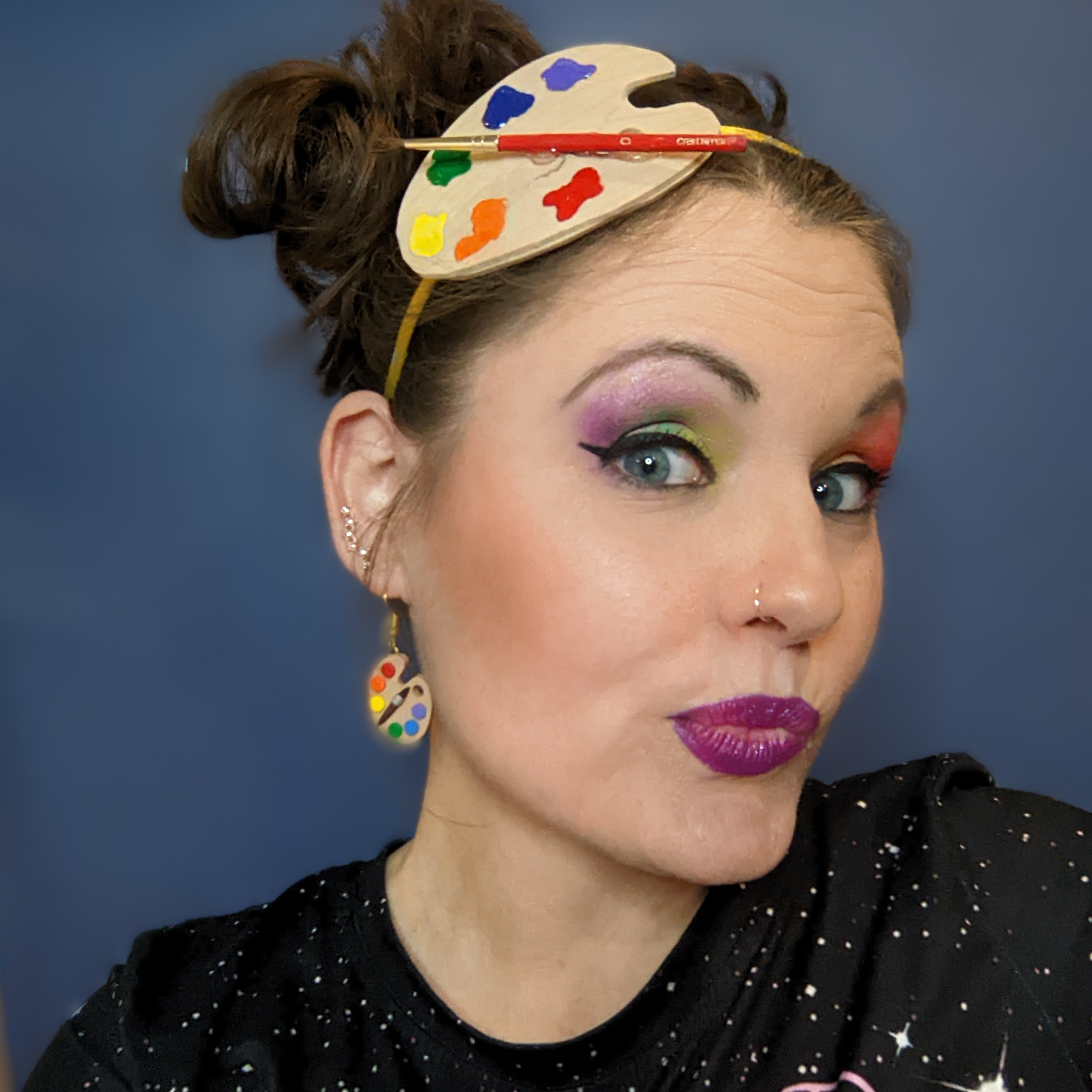 image of Morgan Cullen with a paint palette head band and earrings and rainbow eyeshadow