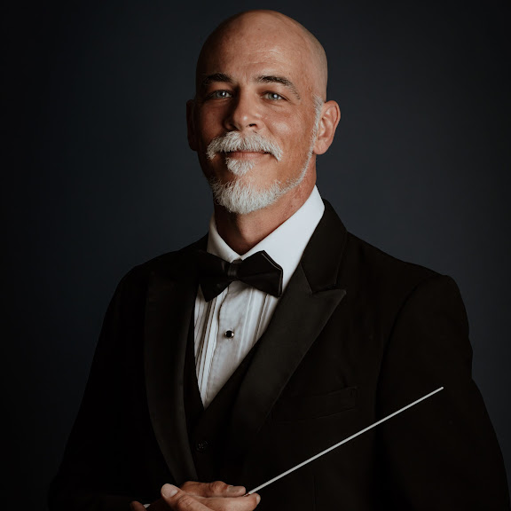 Joseph Daigle wearing a tuxedo and holding a conducting baton