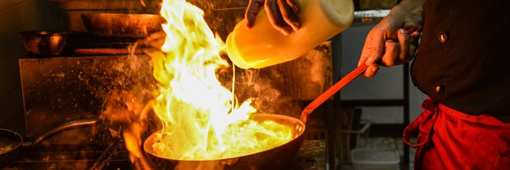 close up of yellow flames on stove top while adding cooking oil to pan