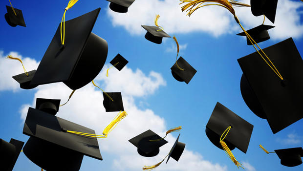 graduation caps in the air with cloudy blue sky background