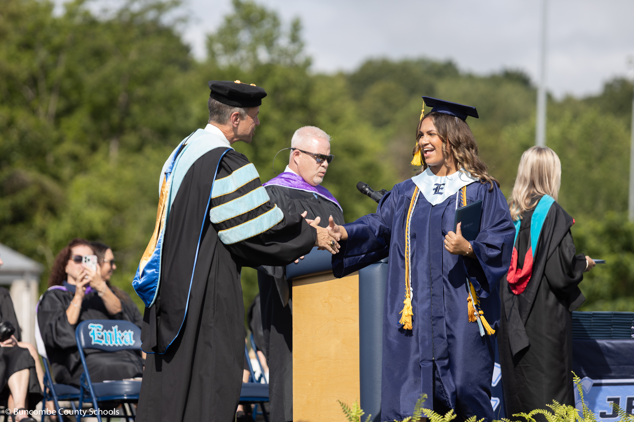 Student walking across the stage at Enka graduation, shaking Superintendent Rob Jackson's hand. 